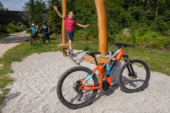 Mädchen balanciert auf einer Slackline, im Vordergrund steht ein E-MTB