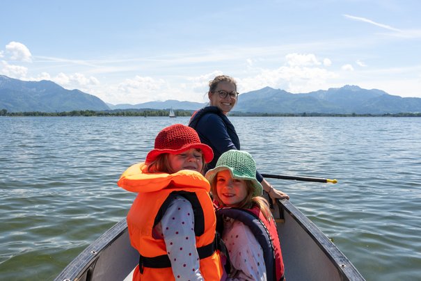 Mutter und zwei Kinder paddeln im Kanu auf dem Chiemsee