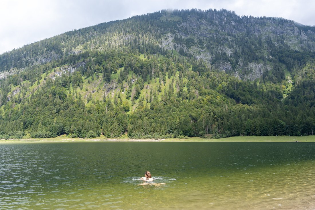 Frau schwimmt im See mit Bergpanorama 