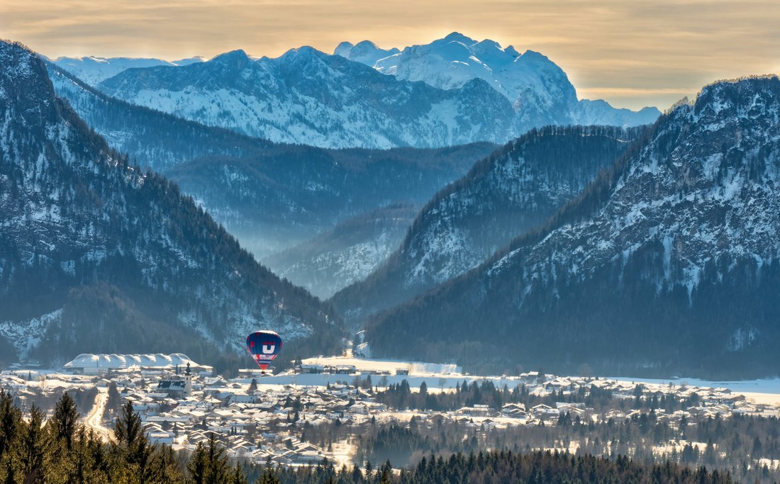 Ein Ballon fährt ins winterliche Inzell mit Bergpanorama im Hintergrund