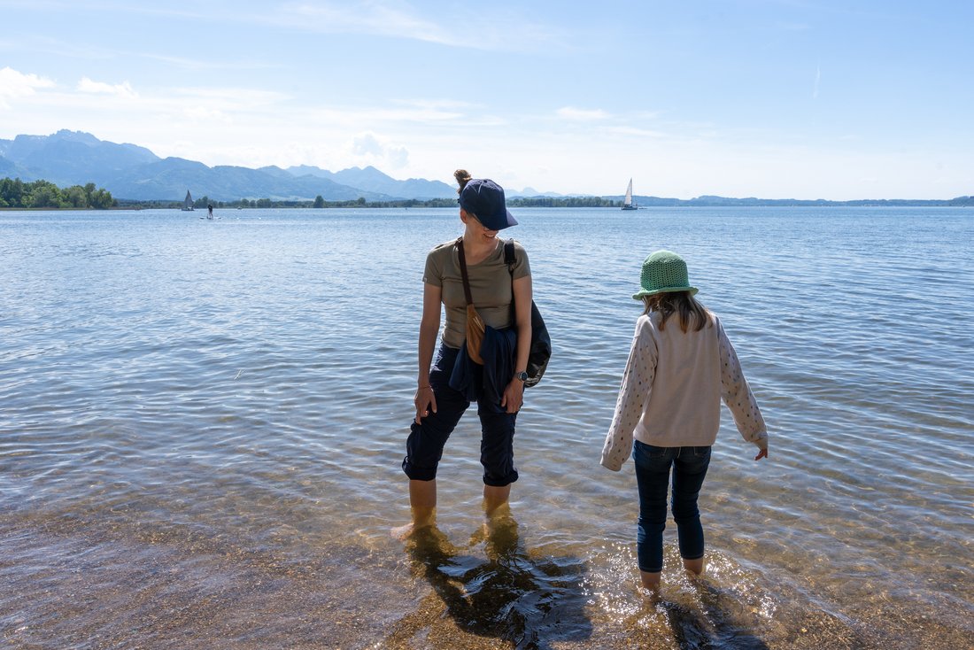 Eine Frau und ein junges Mädchen stehen im Wasser des Chiemsees in Übersee.