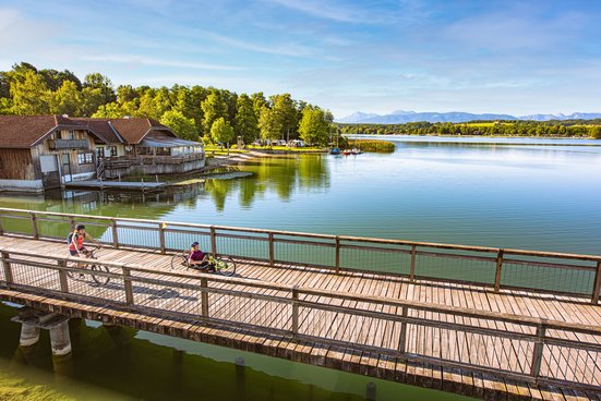 Handbikerin auf dem Liegebike und Radfahrerin auf der Brücke am Waginger See