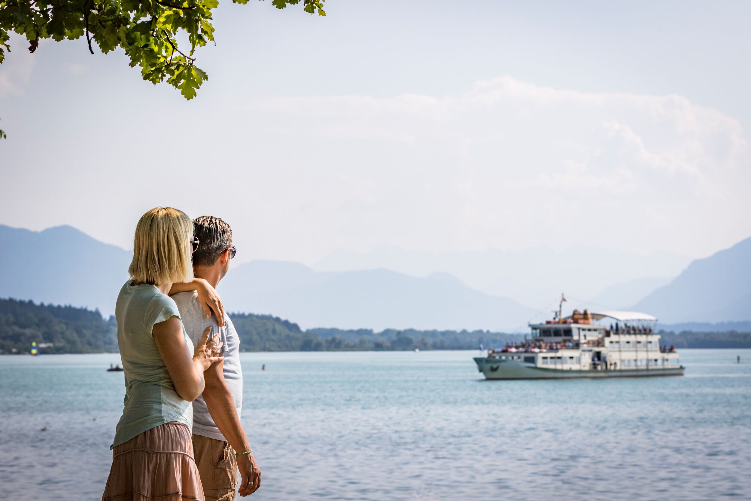 Paar schaut über den Chiemsee, im Hintergrund die Chiemsee Schifffahrt